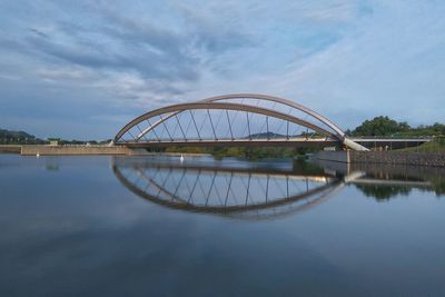 Arch bridge over river against sky