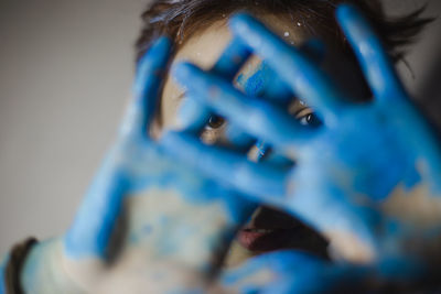 Close-up portrait of woman showing blue paint on palms
