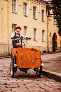 Rear view of man riding motor scooter on street