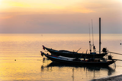 Boat moored in sea against sky during sunset