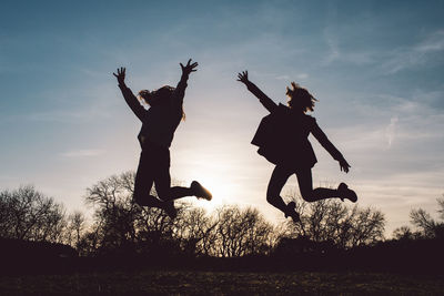 Silhouette people jumping at sunset