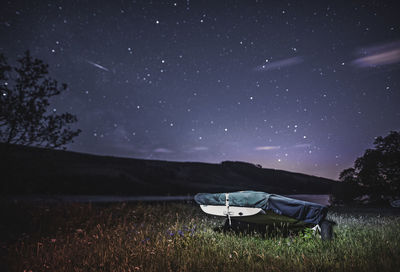 Boat on land against star field at night