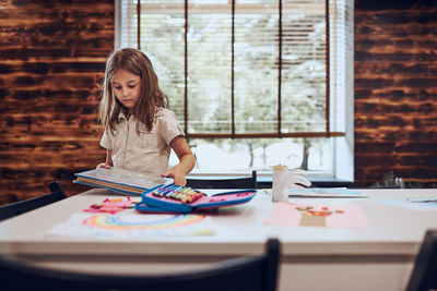 Girl doing homework, learning, drawing pictures, doing puzzles in school library. primary education