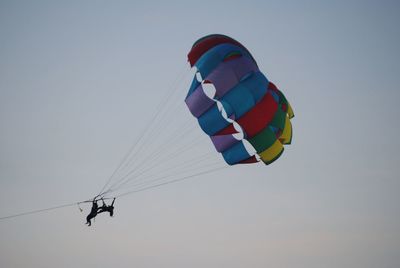 Low angle view of parachute flying against sky