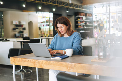 Beautiful stylish young woman plus size body positive using laptop at the beauty salon office