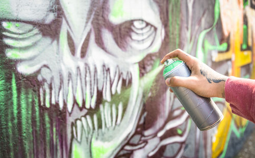 Midsection of person holding graffiti on wall