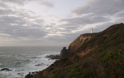 Scenic view of sea by cliff against sky