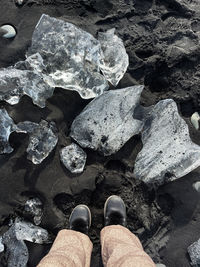 Woman standing next to the ice in the black sand beach in iceland