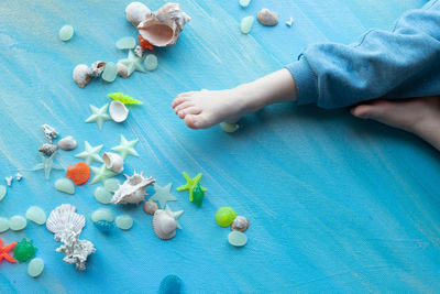 Baby feet on seashells summer background. seashells, on blue paint strokes. place for text.