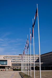 Low angle view of flags on building against blue sky