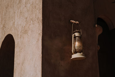 Low angle view of electric lamp hanging on wall