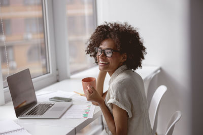 Portrait of young woman using mobile phone at home