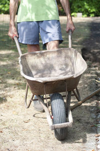 Gardener man in dirty work clothes, rolls a rusty cart with a bucket,spring work