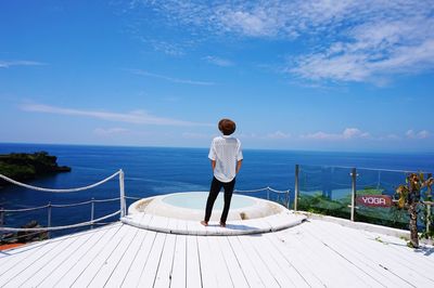 Rear view of man standing by sea against sky