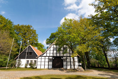 House amidst trees on field against sky