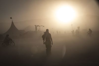 Silhouette people riding on field against sky