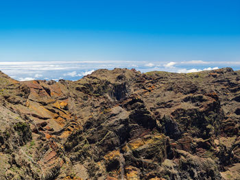 Scenic view of rocky mountains and sea against blue sky