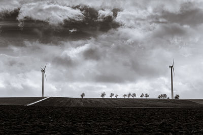 Wind turbines on field against sky