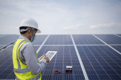 Rear view of man standing on solar panel