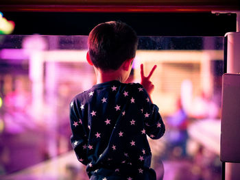 Rear view of man standing at illuminated nightclub