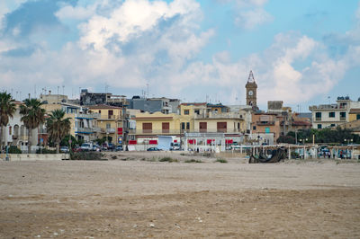 Houses by buildings in city against sky