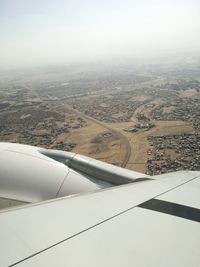 Aerial view of airplane wing over landscape against sky