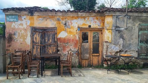 Empty chairs and tables against old building