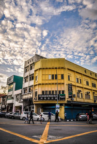 Cars on city street against cloudy sky