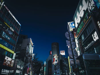 Low angle view of illuminated buildings against clear sky at night