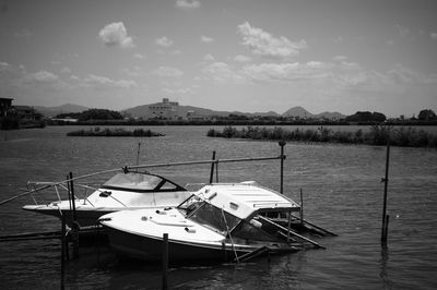 Broken boats moored in lake against sky