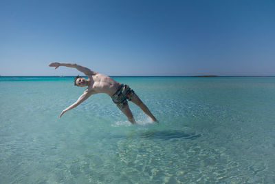 Man surfing in sea against clear sky