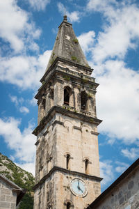 Low angle view of clock tower amidst buildings against sky