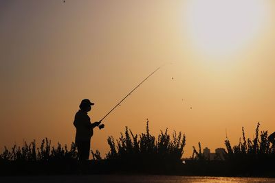 Silhouette man fishing at sunset