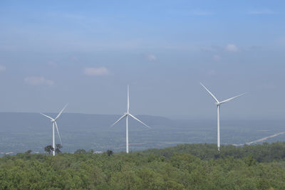 Wind turbines on field against sky