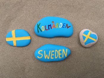 High angle view of painted pebbles with text on sand