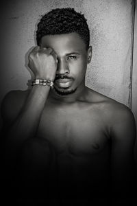 Portrait of handsome young man sitting against wall