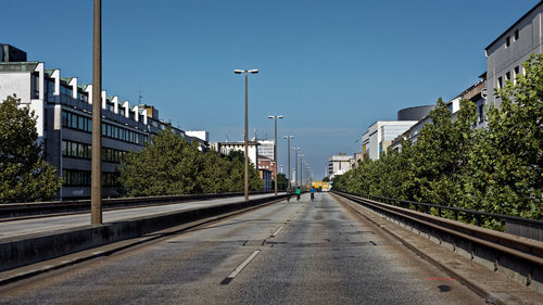 Road amidst trees in city against clear sky