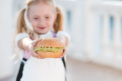 Girl hold fresh hamburger with lettuce closeup. fast food. junk food. back to school. good morning