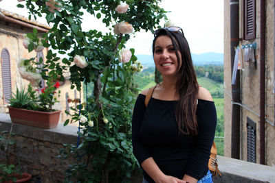 Portrait of young woman standing against plants