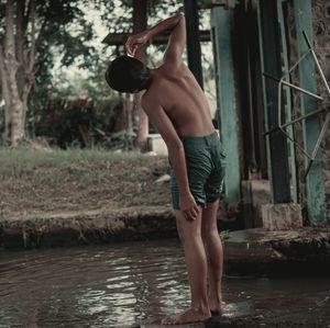 Full length of shirtless man standing in water