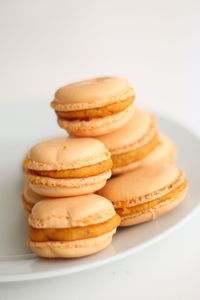 Close-up of orange macaroons in white plate on table