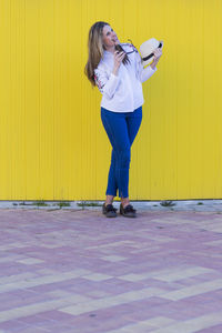 Side view of woman standing against yellow wall