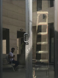 Side view of man looking through window of building