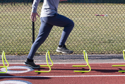 Side view of a high school boy in the a-position standing over one foot high yellow mini hurdles.