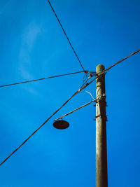 Low angle view of telephone pole against blue sky