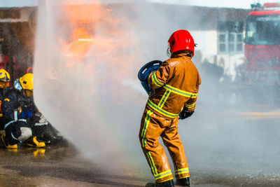Rear view of firefighter extinguishing fire