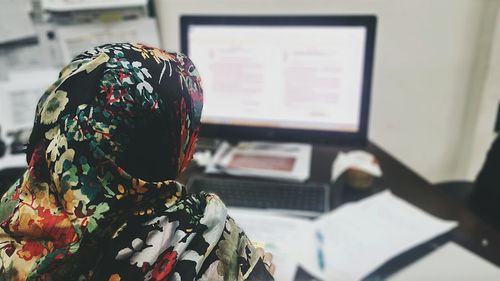 Rear view of businesswoman wearing hijab using computer at office