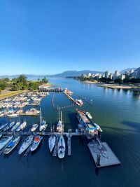 Sailboats moored in sea against clear blue sky