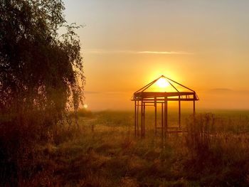 Gazebo on field against sky during sunset