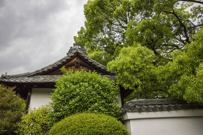 House amidst trees and building against sky